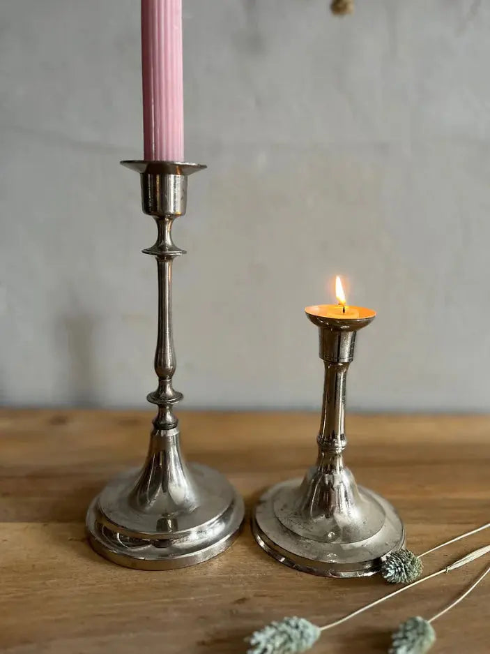 Composition de bougeoirs en laiton de différentes tailles et d'un chandelier en verre ciselé sur un meuble en bois brut.