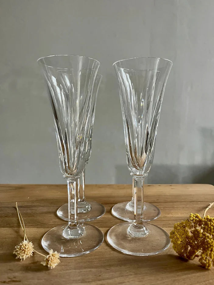 4 flûtes en cristal taillé sur fond bois avec des fleurs