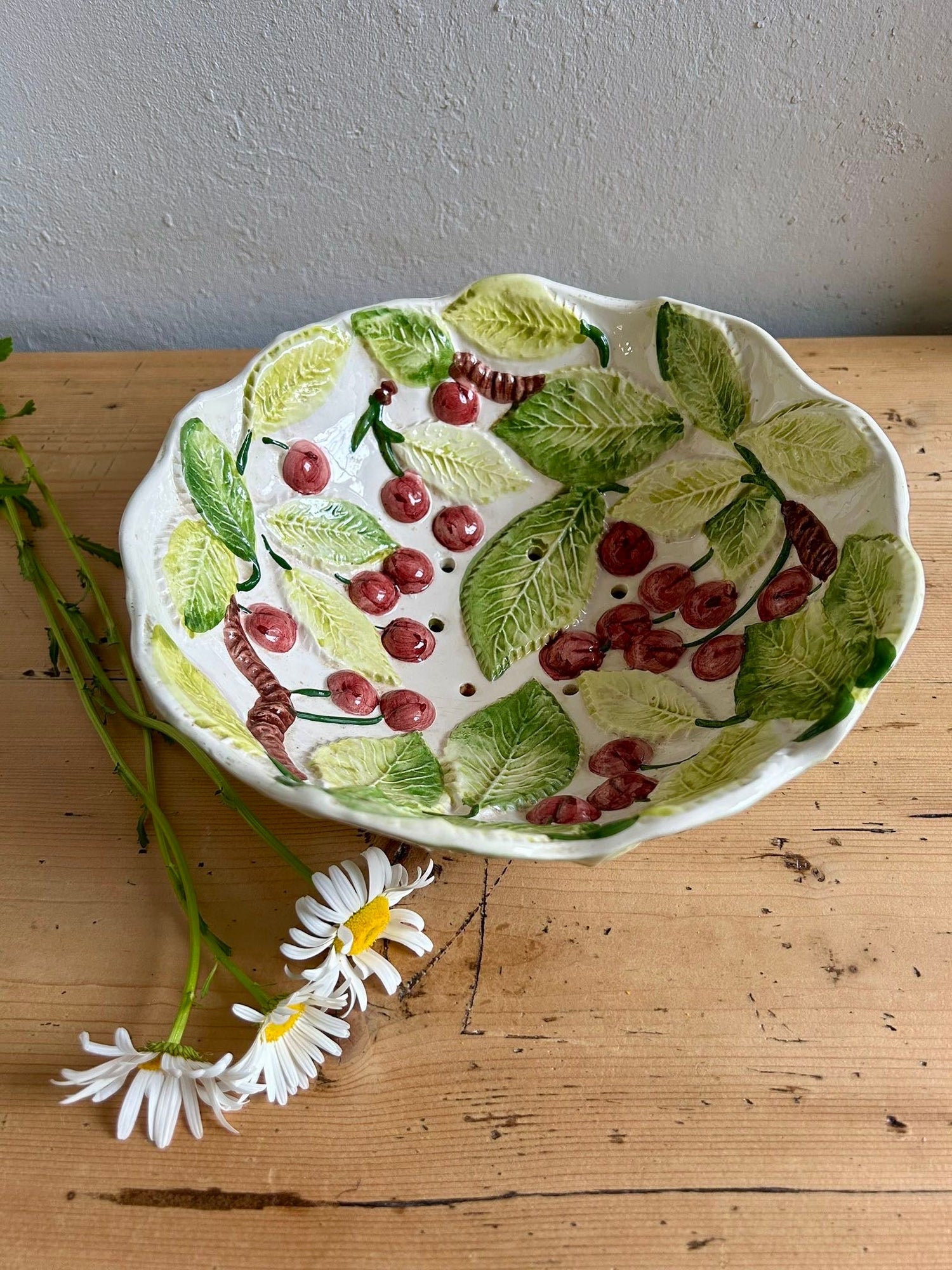Coupe à cerises égouttoire barbotine céramique blanche reliefs cerises feuilles vert table bois marguerites