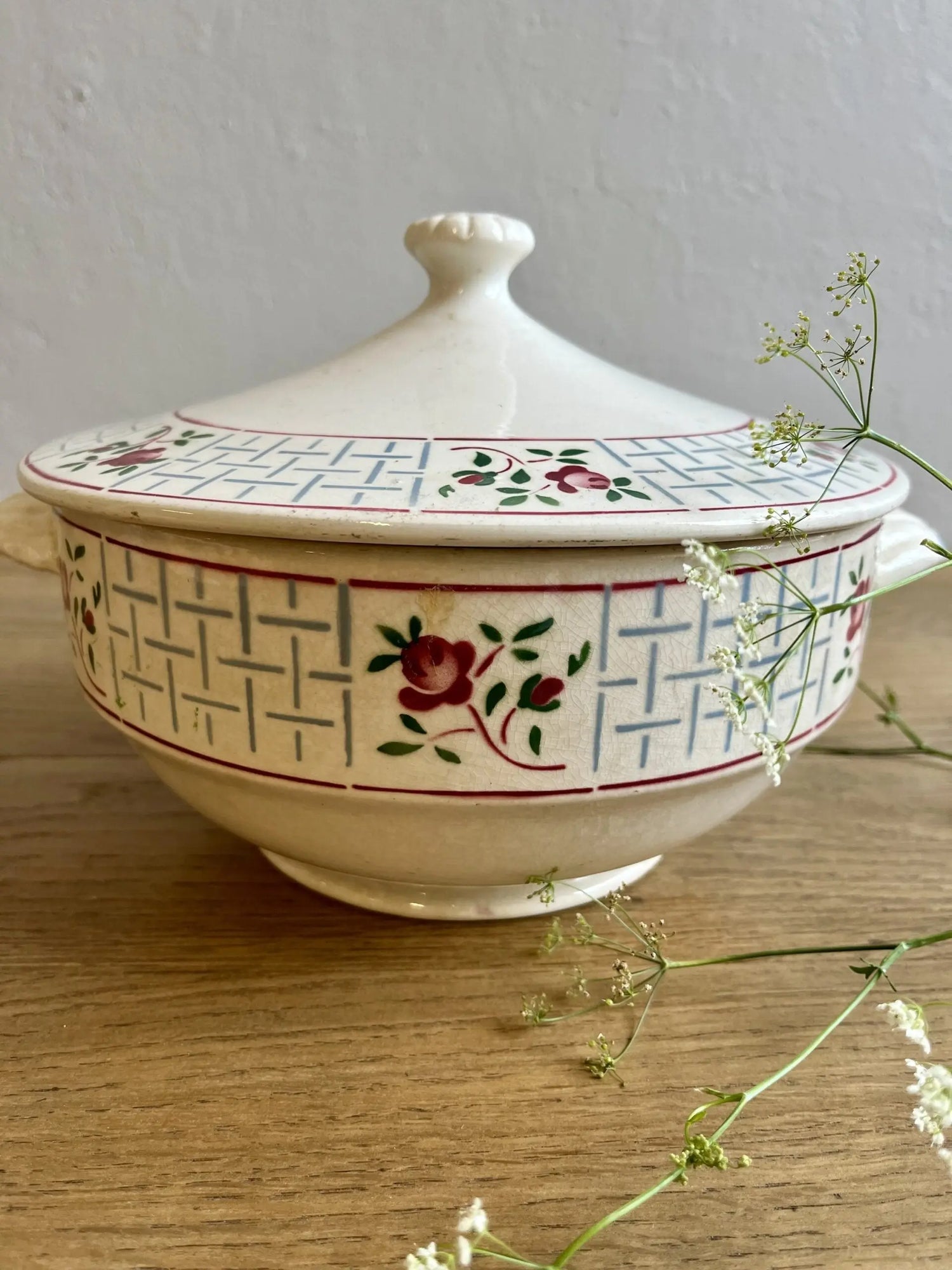 Soupière vintage en faïence détournée en saladier sur une table en bois clair.