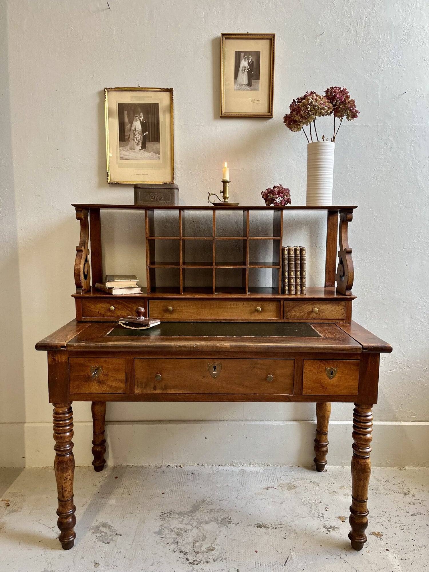 Bureau à gradin ancien pieds tournés présenté avec des livres et des cadres anciens